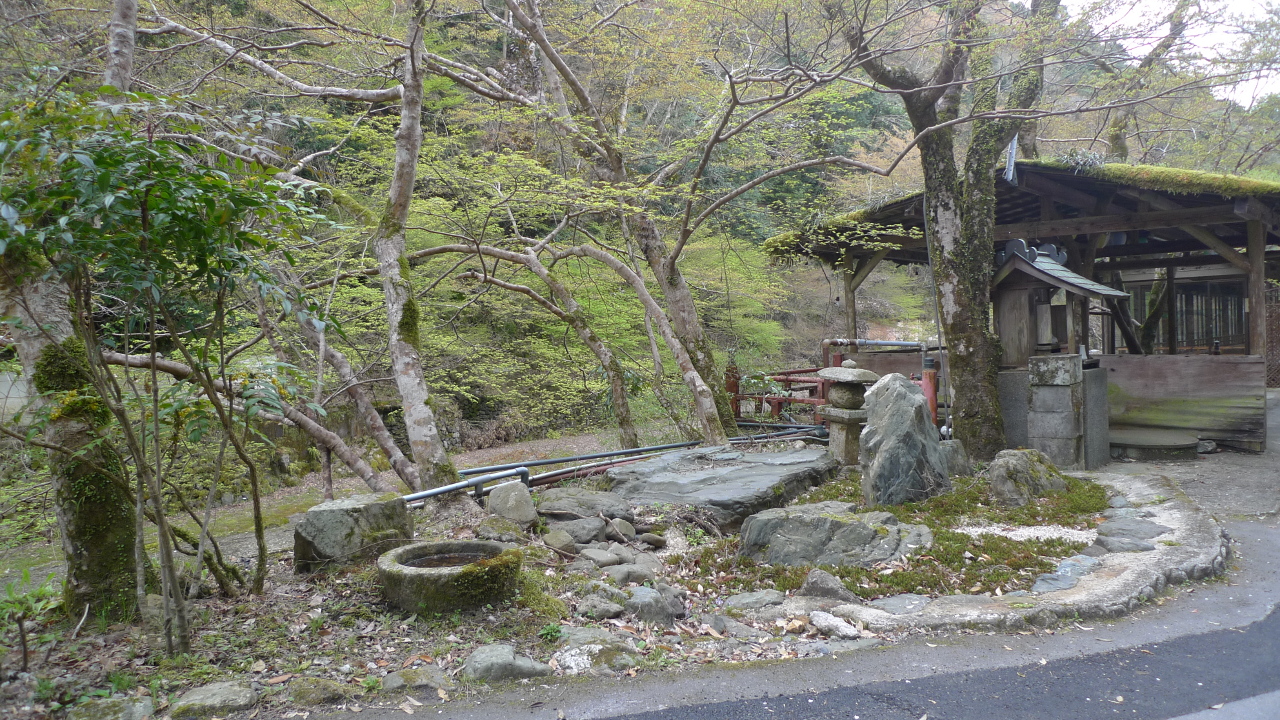 Sanctuaire shinto miniature, composé d'un petit bassin et d'une petite structure de pierre.