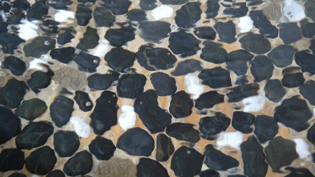Des pierres polies noires et blanches, dans l'eau.